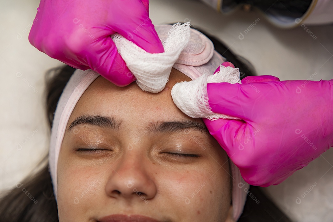 Mulher jovem recebendo procedimentos estéticos por uma profissional do ramo