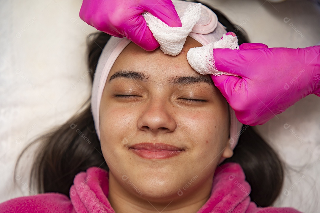 Mulher jovem recebendo procedimentos estéticos por uma profissional do ramo