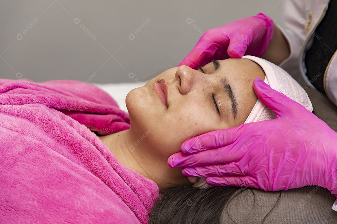 Mulher jovem recebendo procedimentos estéticos por uma profissional do ramo