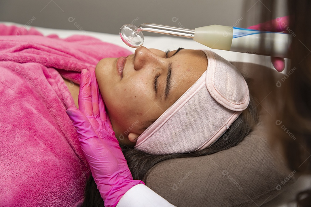 Mulher jovem recebendo procedimentos estéticos por uma profissional do ramo