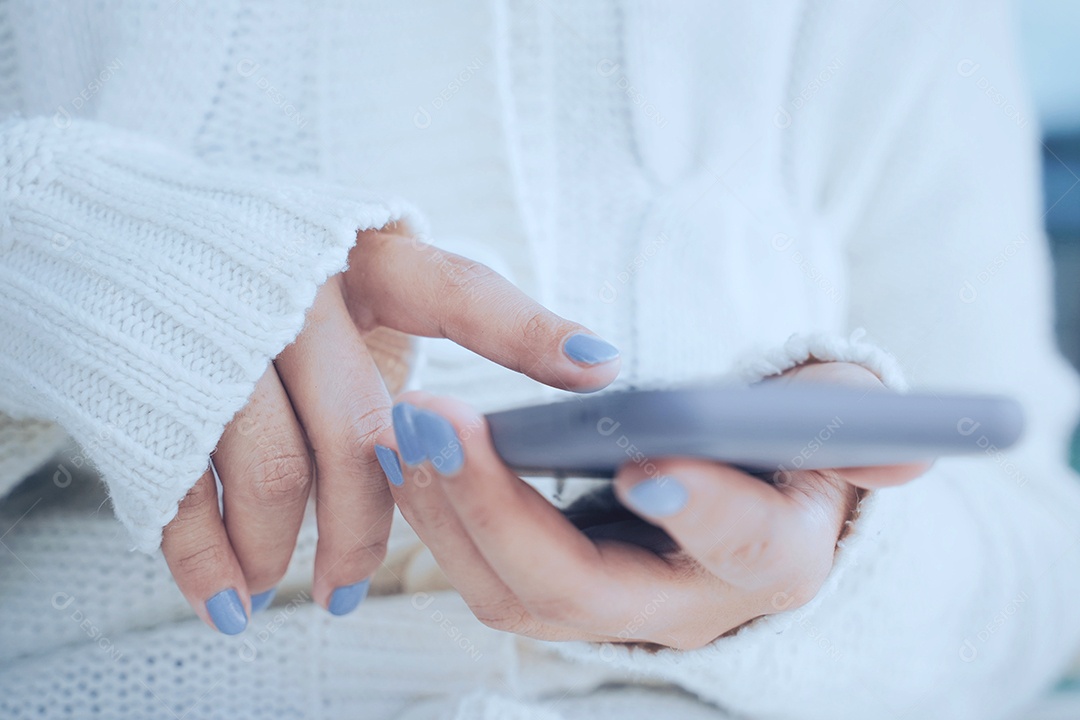 Feche as mãos da mulher usando smartphone em clima frio