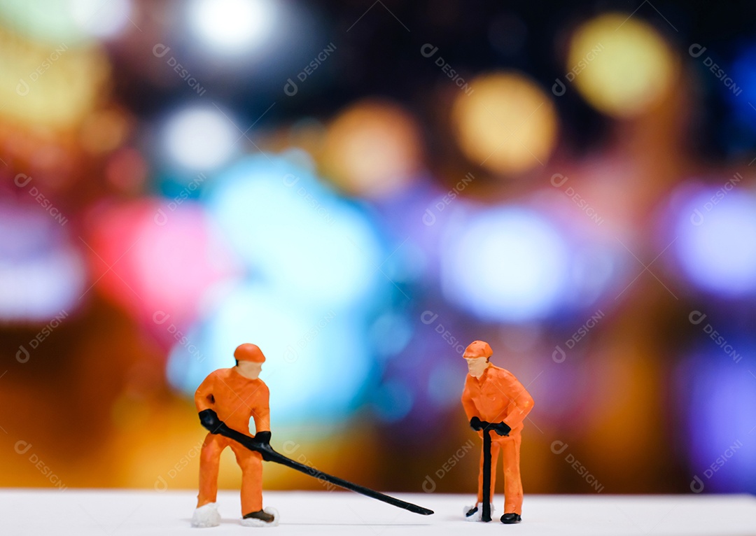 Trabalhador de pessoas em miniatura repara rua à noite com luz bokeh
