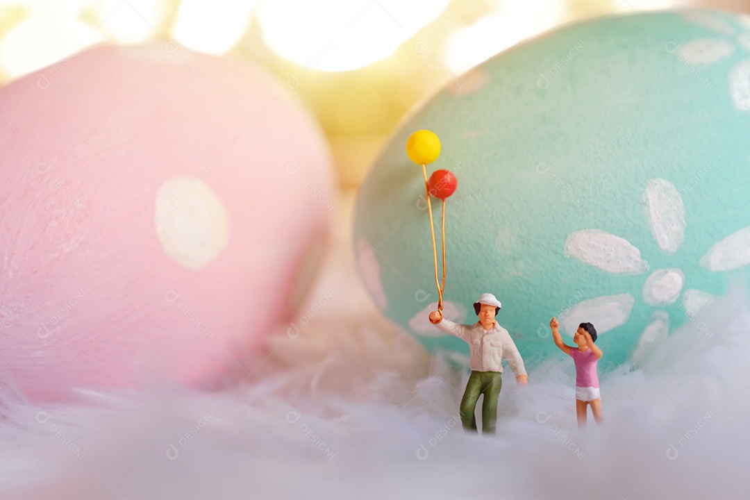 Família de pessoas em miniatura segurando balão com pastel e colorido