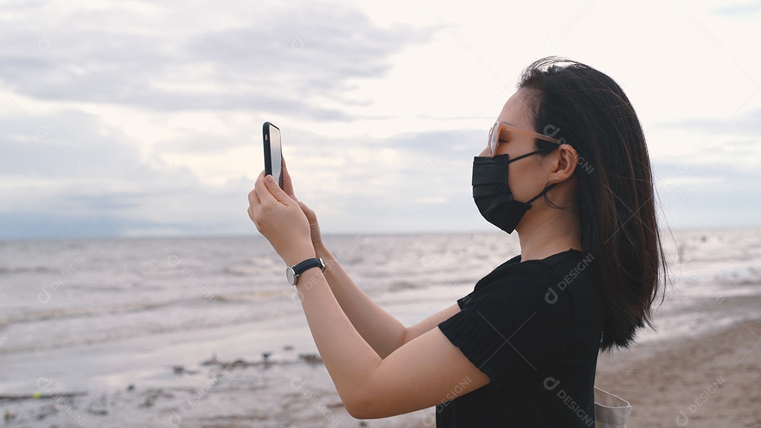 Jovem mulher asiática usando máscara médica e tirando fotos