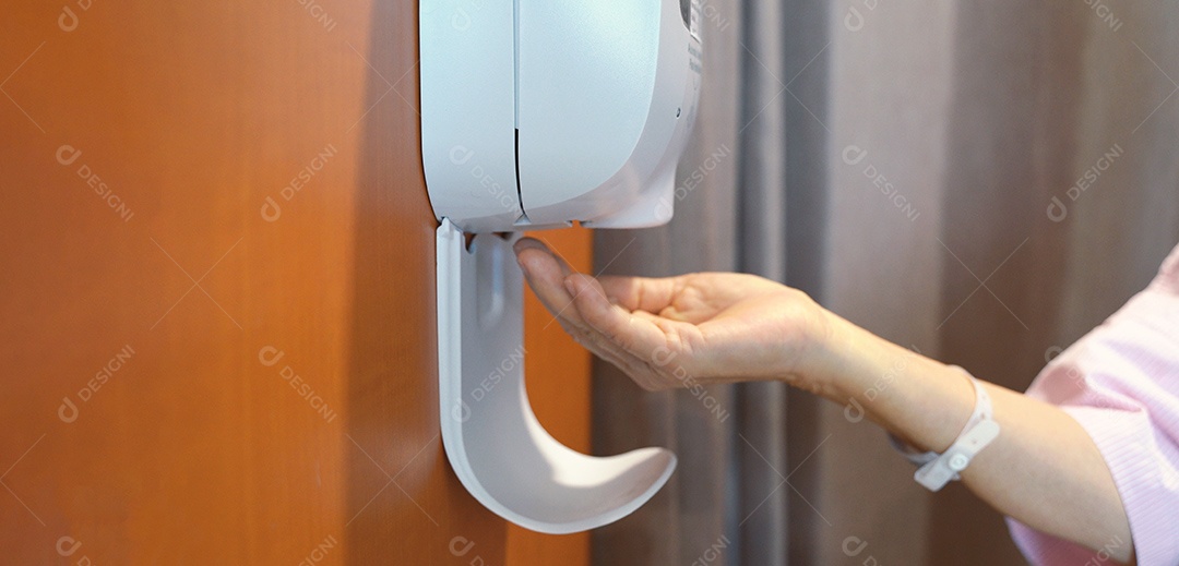 Mulher paciente sênior lavando a mão do desinfetante automático para as mãos