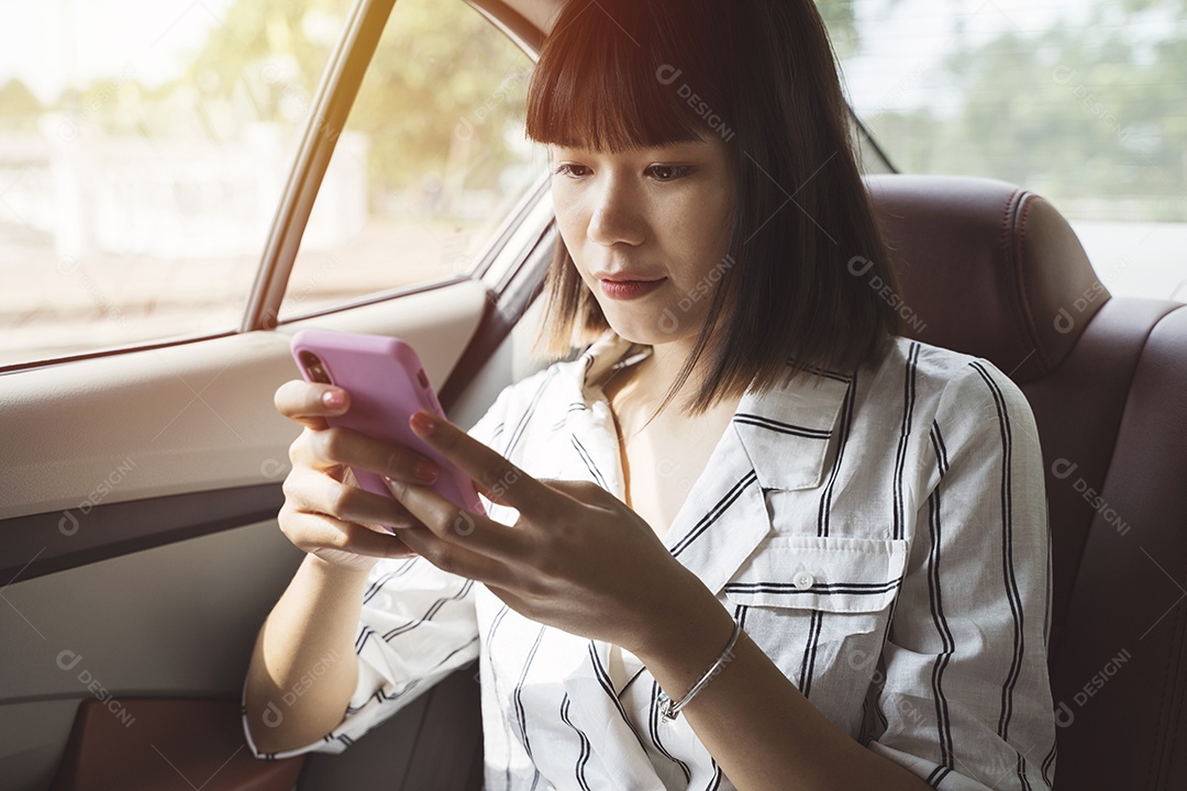 Mulher jovem passageira asiática usando seu smartphone no banco de trás