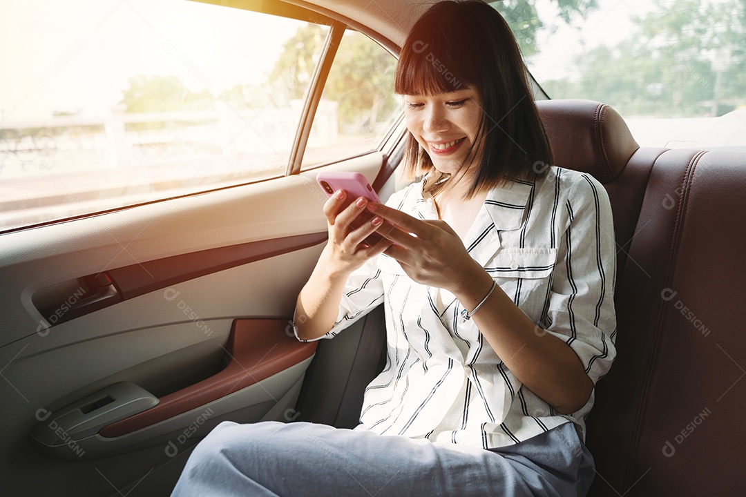 Mulher jovem passageira asiática usando seu smartphone no banco de trás