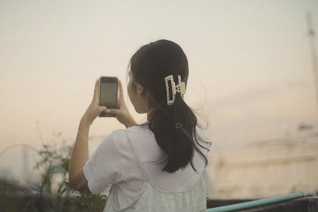 Feliz jovem asiática milenar usando telefone móvel