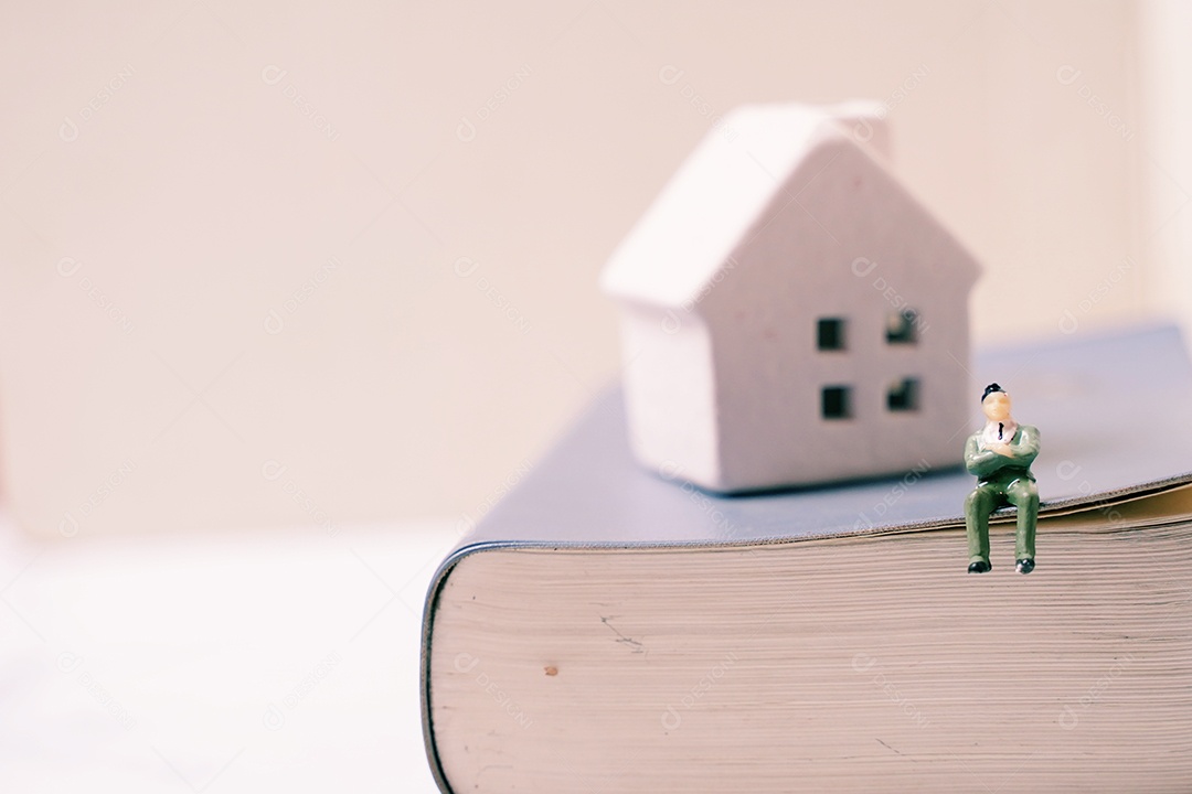 Empresários em miniatura figuram sentados no livro