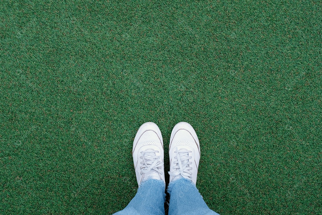 Selfie de pés em sapatos de tênis brancos no fundo da grama verde