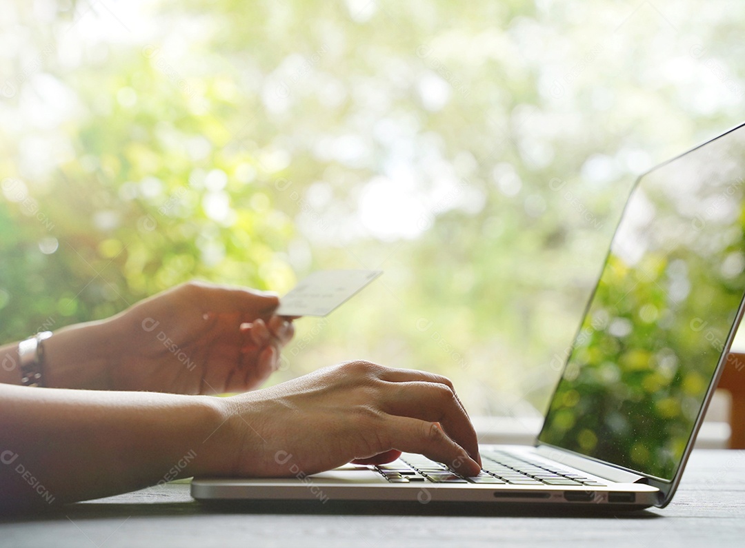 Mão de uma mulher segurando o cartão de crédito e compras on-line na sexta-feira negra