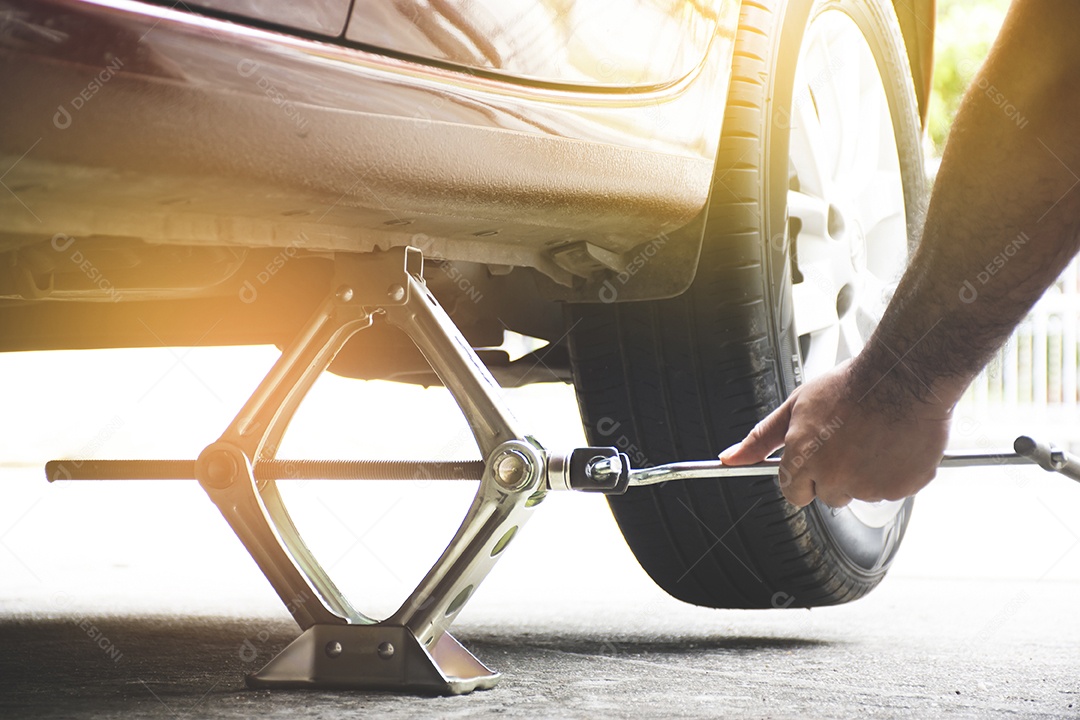 A mão humana estava usando um macaco para levantar a carroceria do carro para consertar