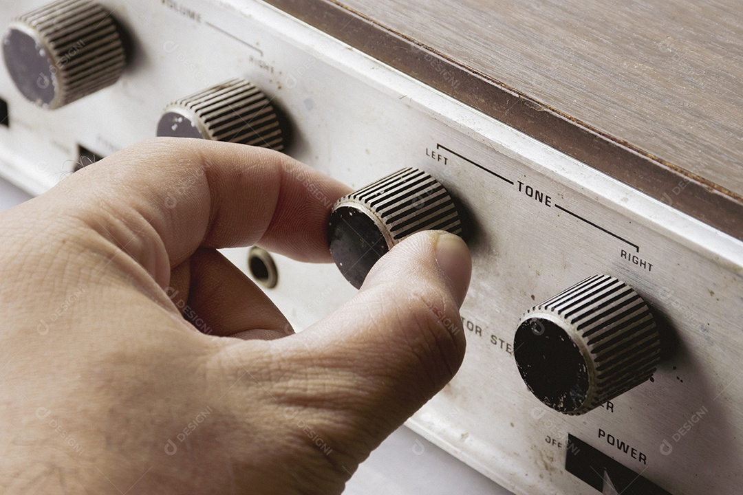 A mão está ajustando o botão de volume de tom do amplificador integrado