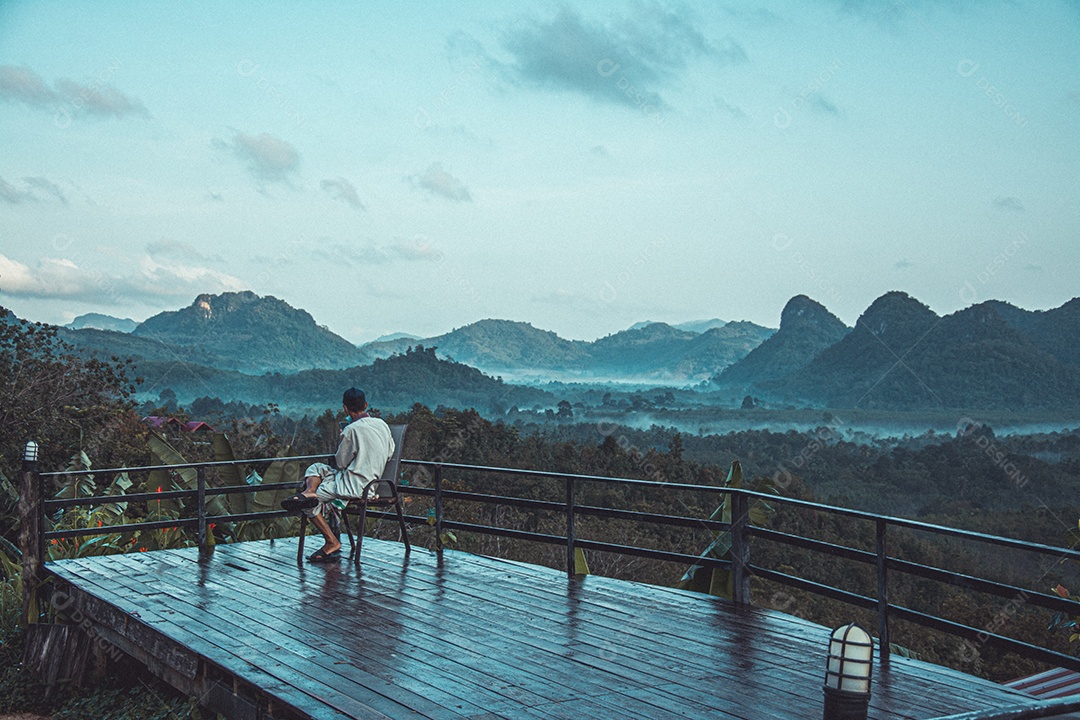 Pessoa sobre varanda de sua casa olhando paisagem floresta