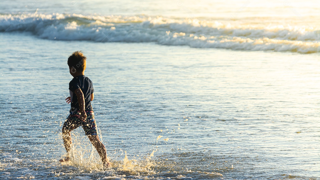 Lindo filho se divertindo na praia no verão