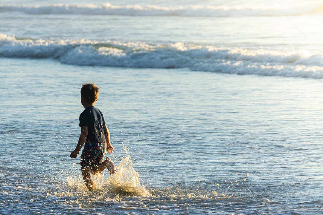 Lindo filho se divertindo na praia no verão