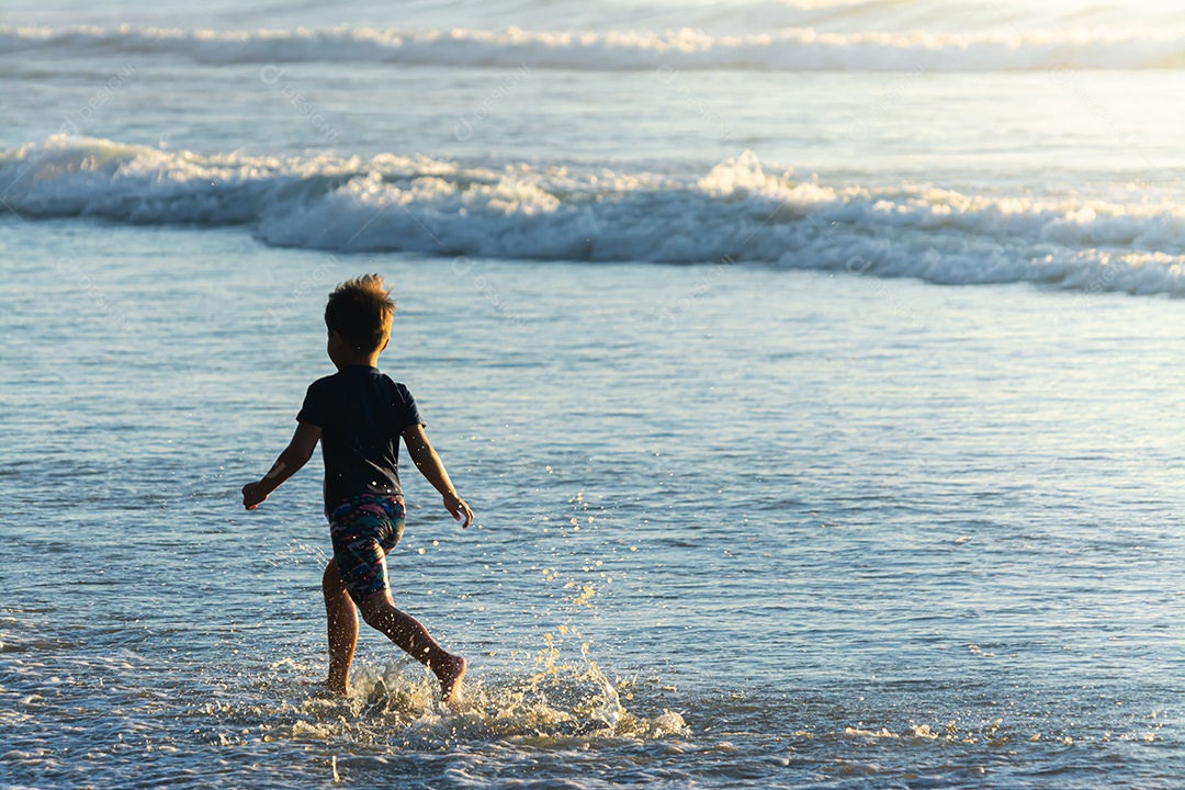 Lindo filho se divertindo na praia no verão