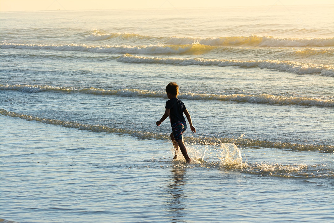 Lindo filho se divertindo na praia no verão
