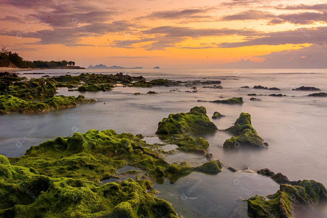 paisagem por do sol nas rochas da praia em primeiro plano