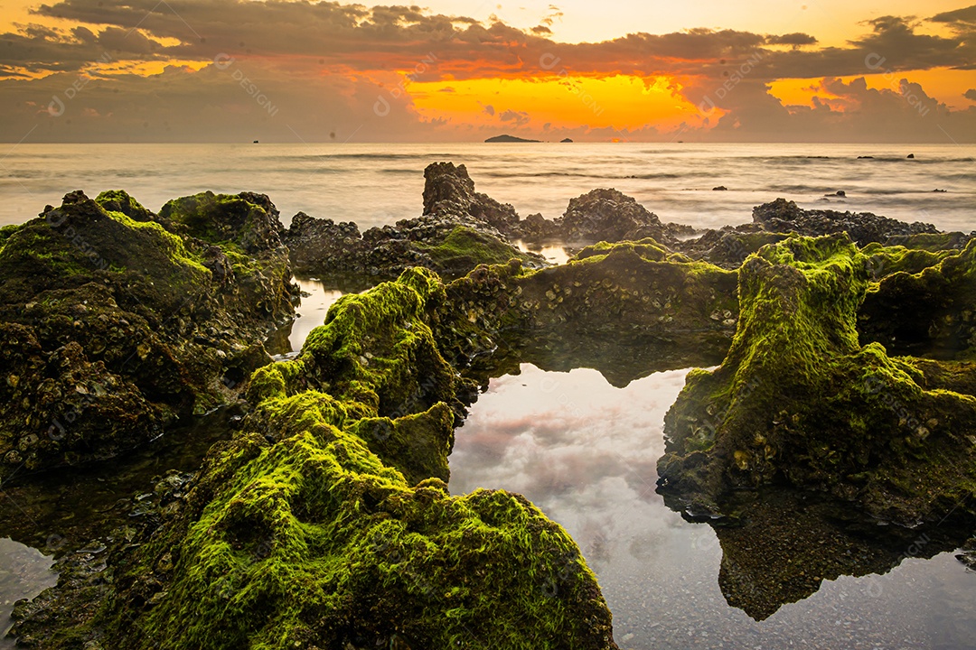 paisagem por do sol nas rochas da praia em primeiro plano