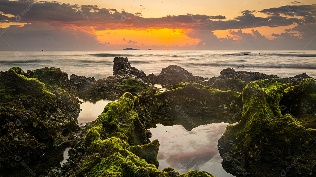 paisagem por do sol nas rochas da praia em primeiro plano