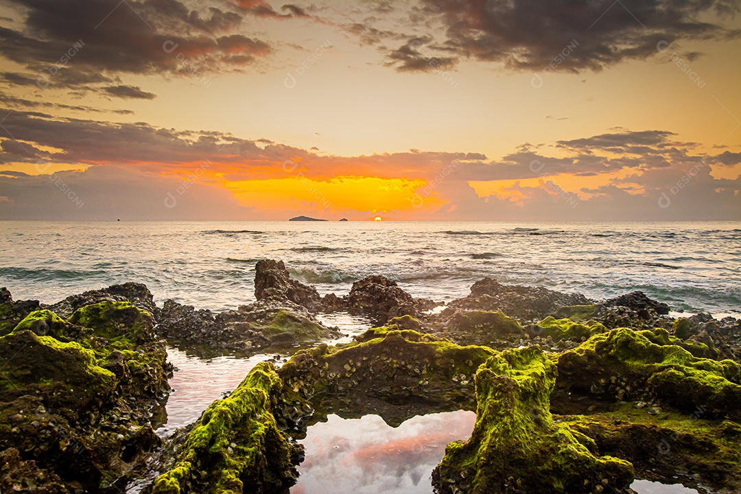 paisagem por do sol nas rochas da praia em primeiro plano