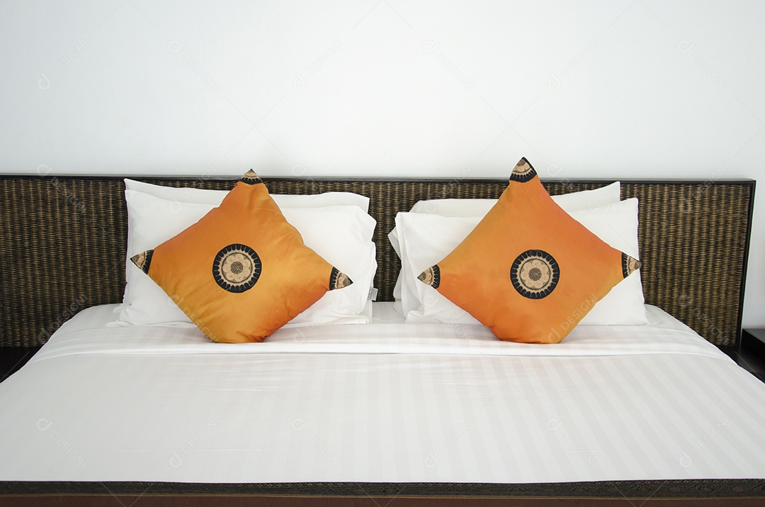 Almofadas laranja na cama arrumada e limpa