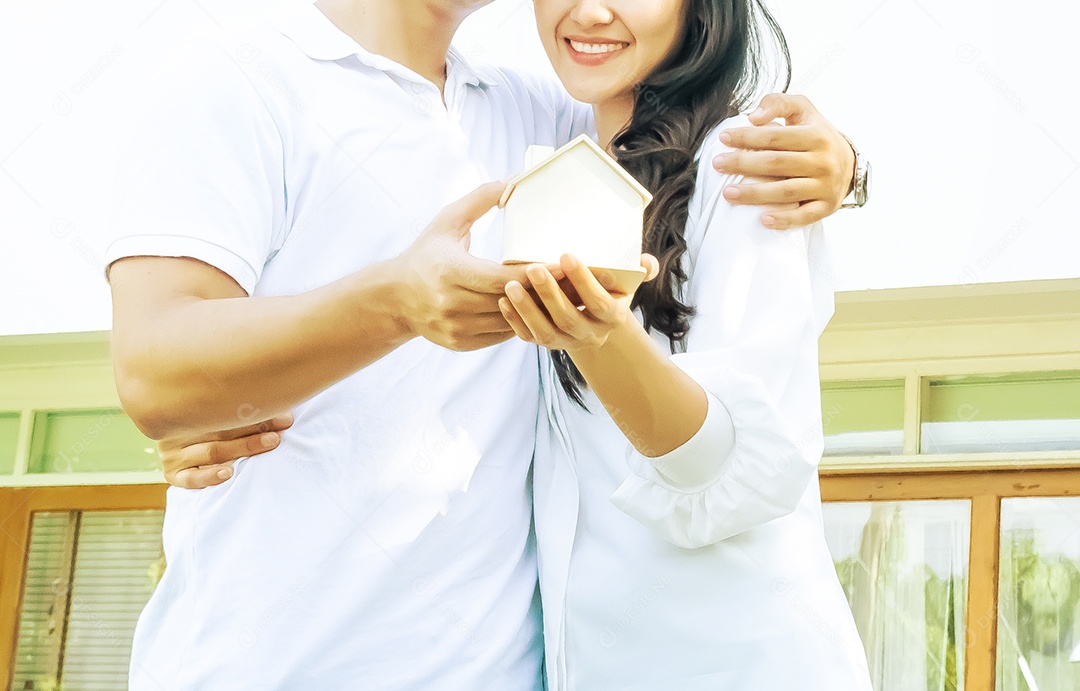 homem e mulher segurando um modelo de casa em suas mãos