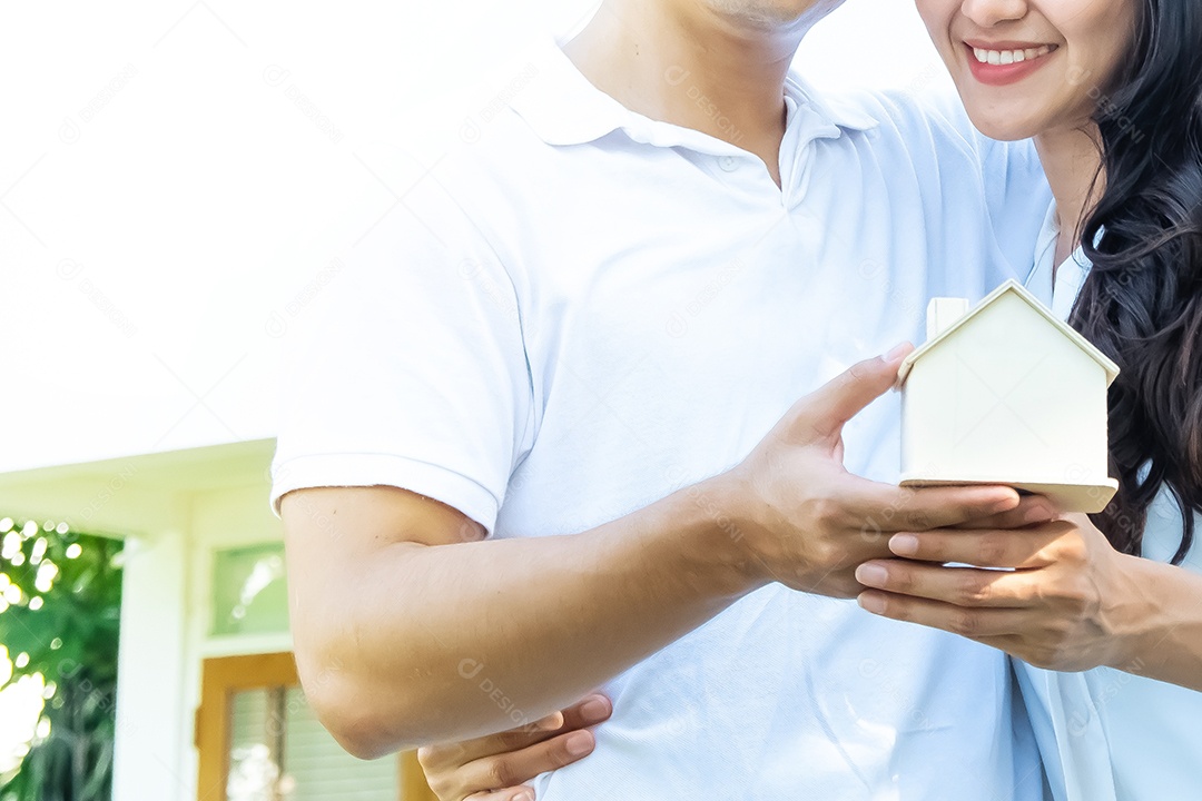 homem e mulher segurando um modelo de casa em suas mãos