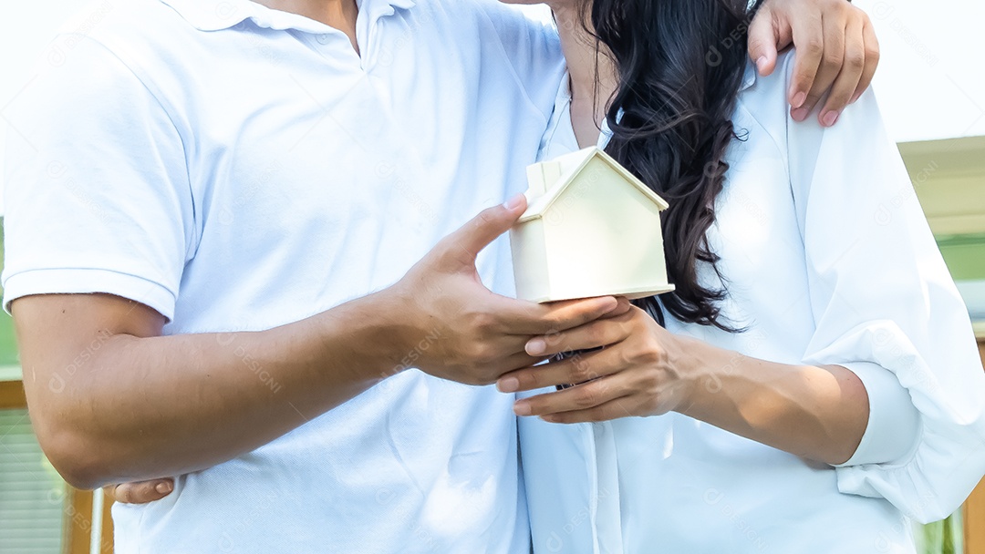 homem e mulher segurando um modelo de casa em suas mãos