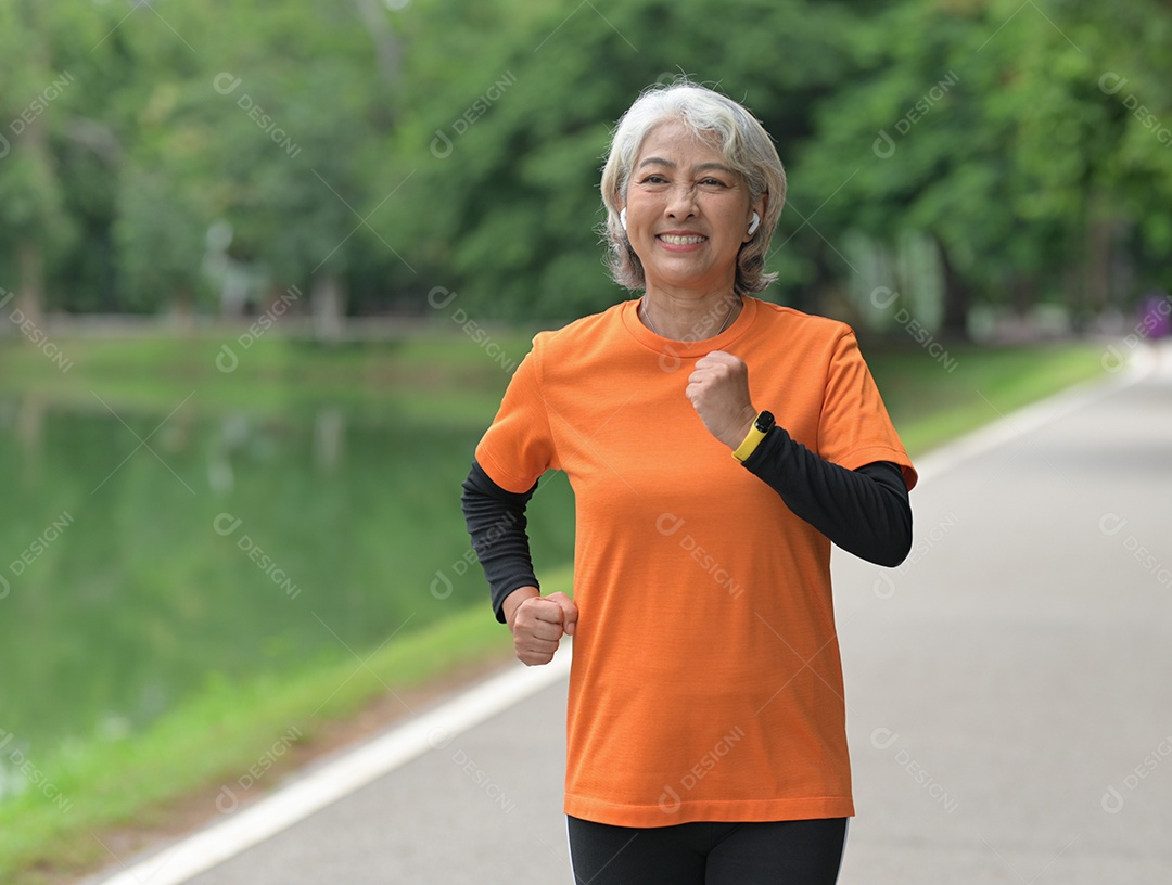 Mulher idosa exercitando-se ao ar livre vigorosamente e alegremente, correndo, halteres.