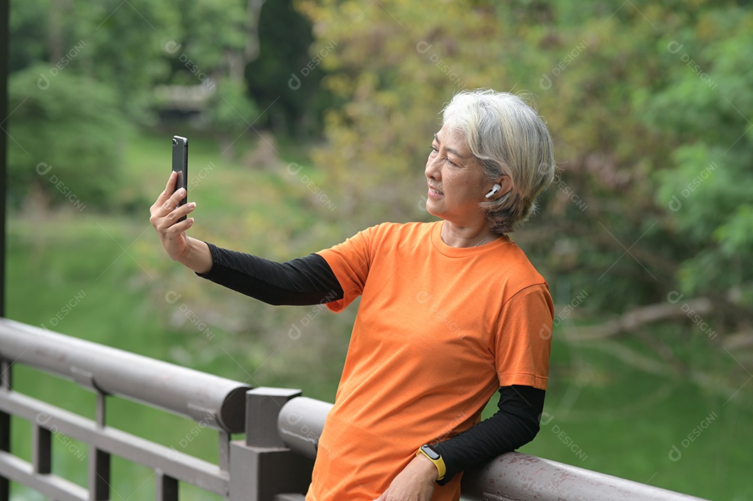 Mulher idosa exercitando-se ao ar livre vigorosamente e alegremente, correndo, halteres.