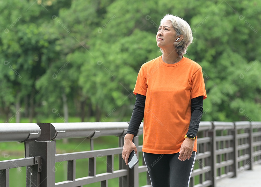 Mulher idosa exercitando-se ao ar livre vigorosamente e alegremente, correndo, halteres.