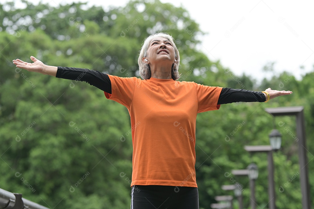 Mulher idosa exercitando-se ao ar livre vigorosamente e alegremente, correndo, halteres.