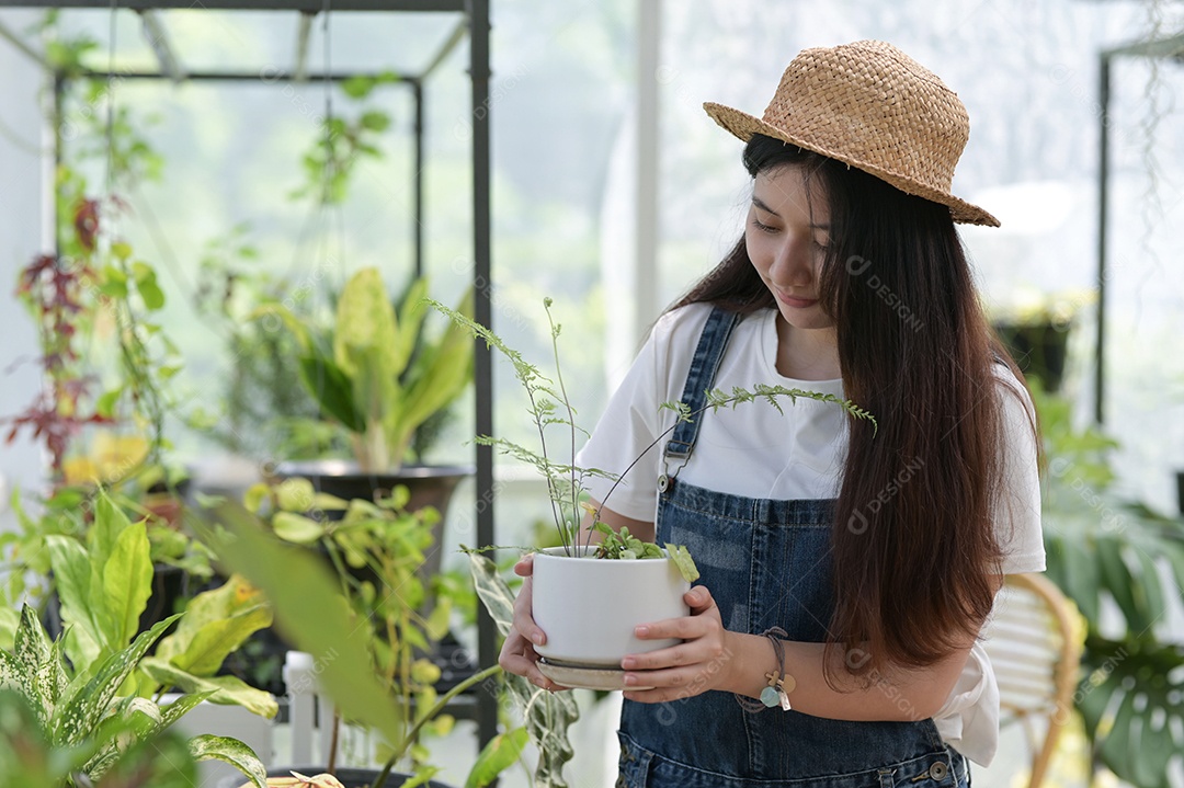 Jovem está cuidando de árvores em uma estufa, plantando árvores em uma estufa, plantando equipamentos, plantando árvores.