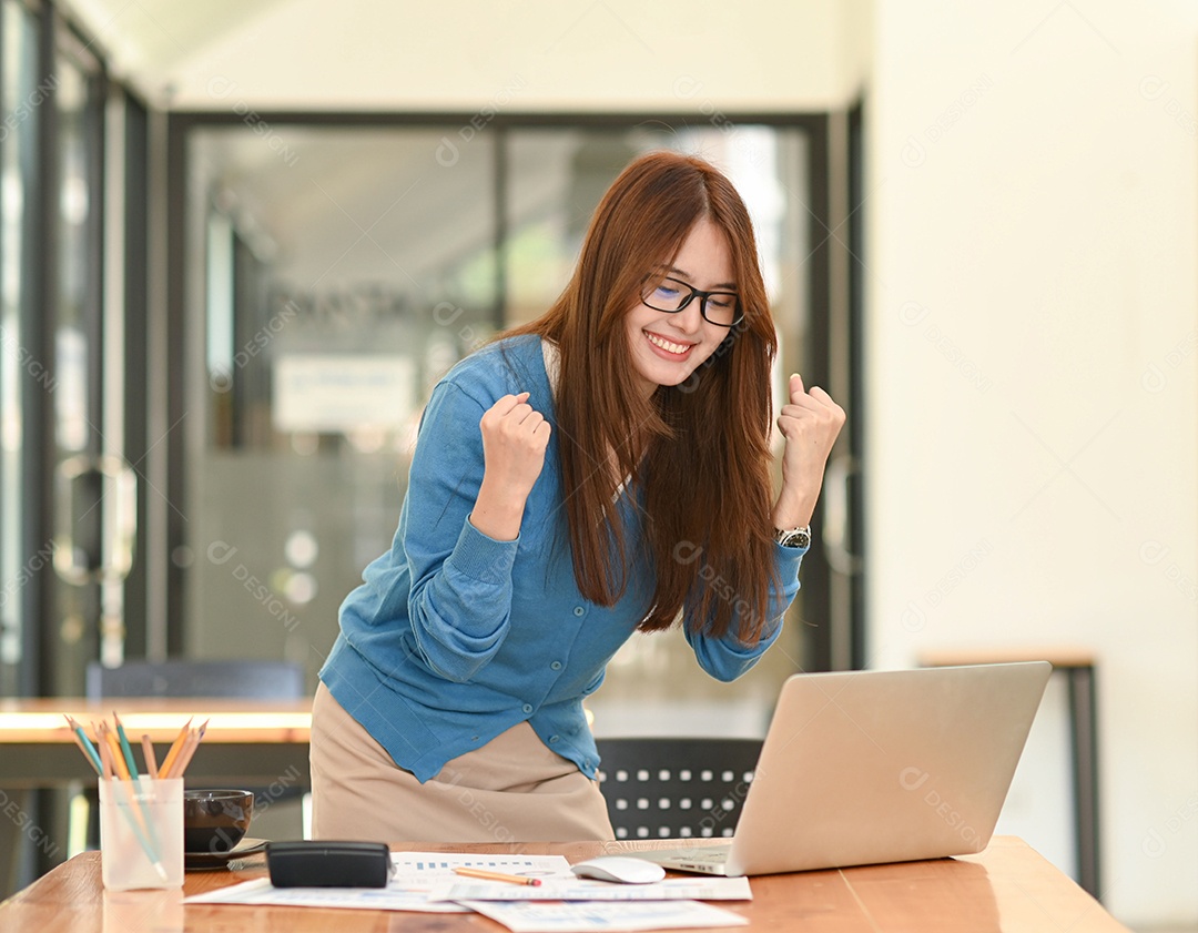 Feliz empresária levantando a mão no sucesso do investimento, olhando para o laptop na mesa de escritório sorrindo, chegando a um negócio, negócio lucrativo.