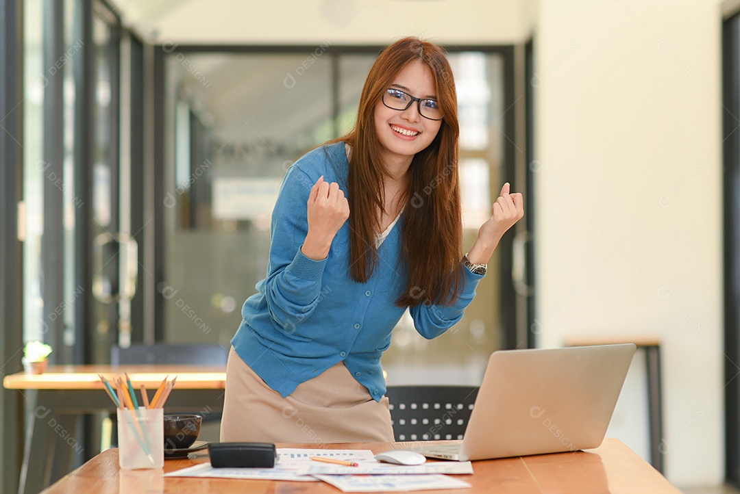 Jovem costura no espaço de trabalho de um designer com equipamento de design, laptop e smartphone em uma oficina.