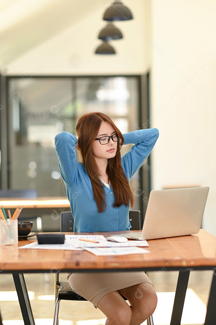 Mulher asiática na camisa azul, esticando os braços para relaxar. Durante o trabalho no escritório, síndrome do escritório, ideia de negócio, equipamento de escritório.