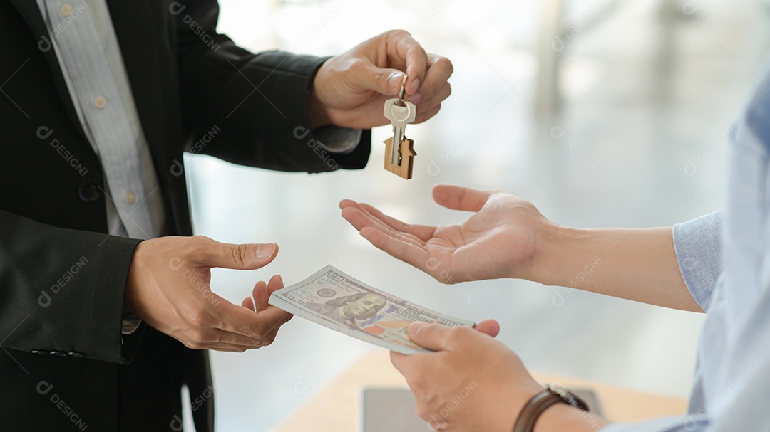 Clientes e proprietários trocam dinheiro e chaves após concordarem em comprar uma casa.