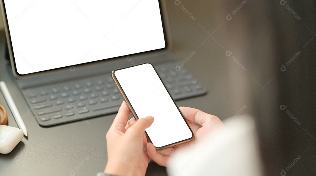 Empresária está usando um smartphone de tela em branco com um laptop.