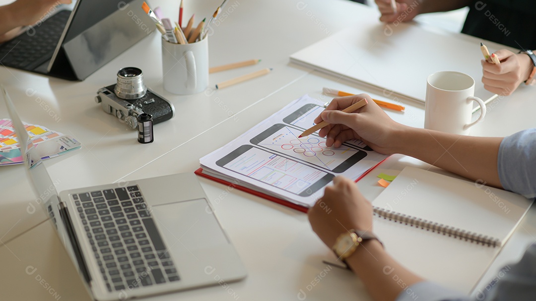 Foto recortada da equipe de jovens designers UX trabalhando no projeto de aplicativo para smartphone com o uso de tablet digital na sala de escritório moderna.