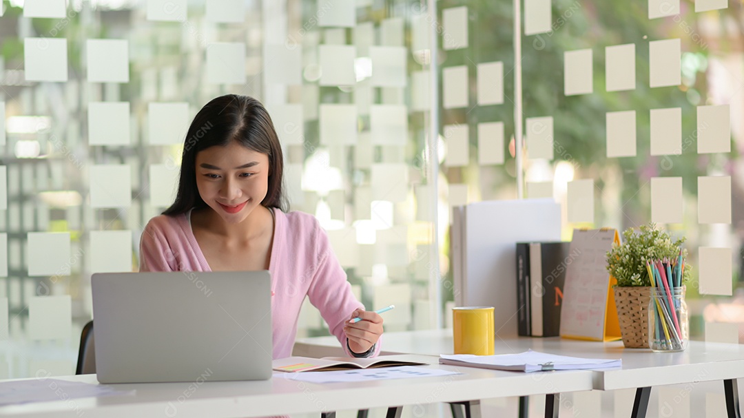 Retrato do jovem investidor usa o laptop com um rosto sorridente para verificar o mercado de ações em um escritório moderno.