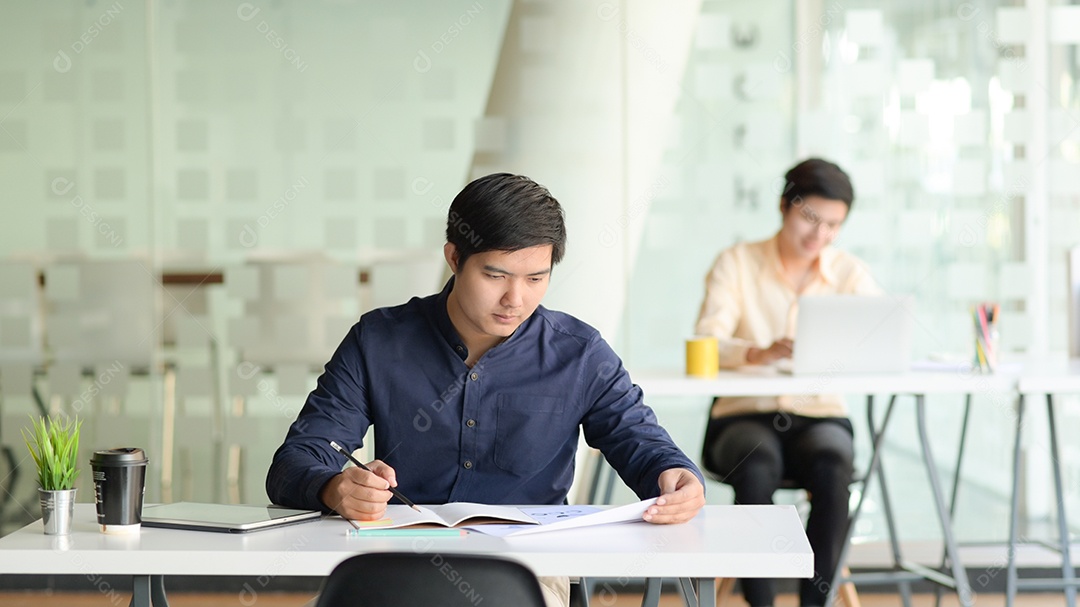 Dois homens de negócios profissionais trabalham juntos em projetos em um escritório moderno.