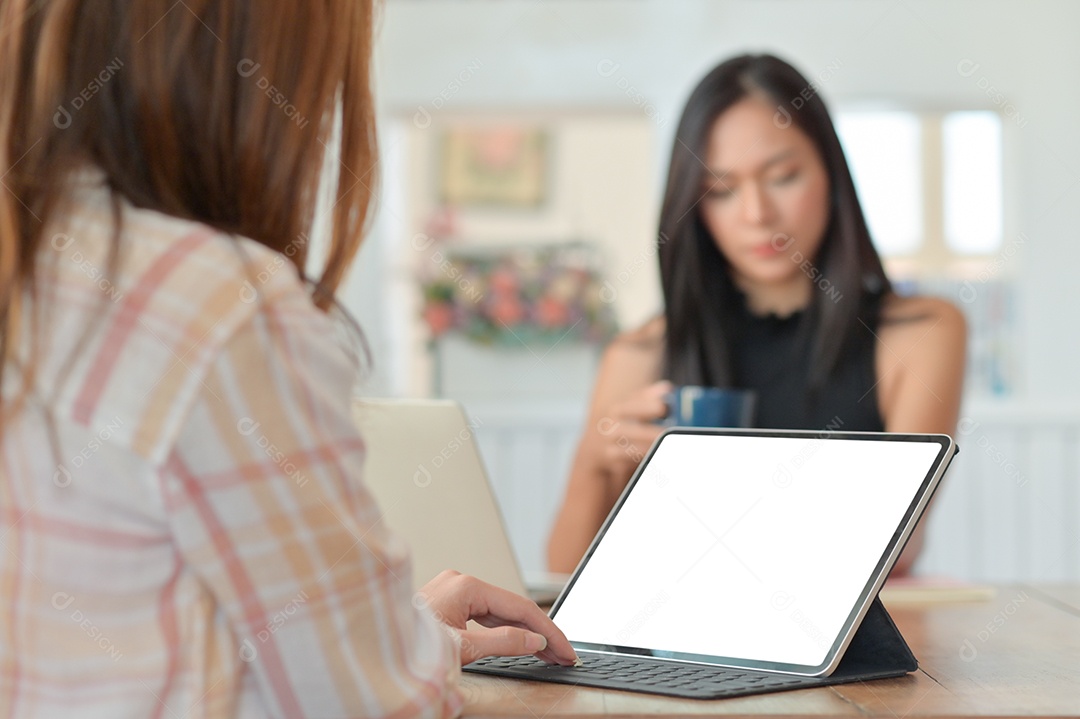 Foto recortada de uma funcionária usando um laptop para apresentar o projeto aos executivos sentados com café nas costas.