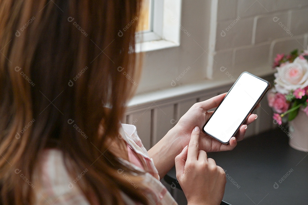 Visão aproximada da mão de uma mulher está usando um smartphone de tela em branco para procurar informações sobre seu projeto