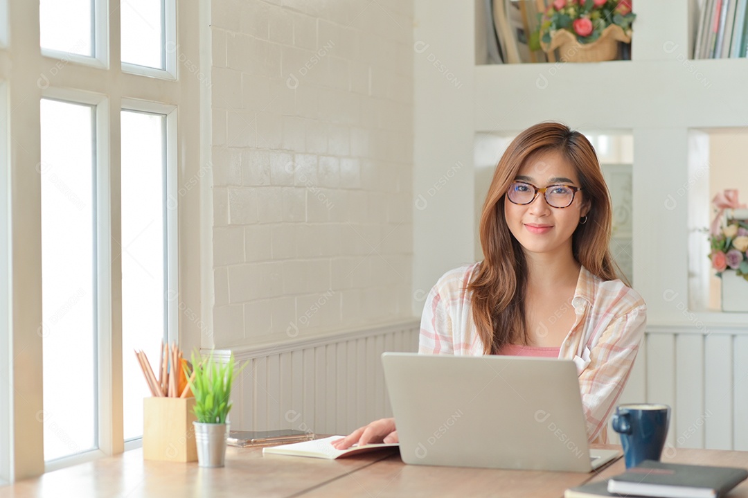 Empresária asiática com um laptop. Ela sorriu alegremente no escritório confortável.