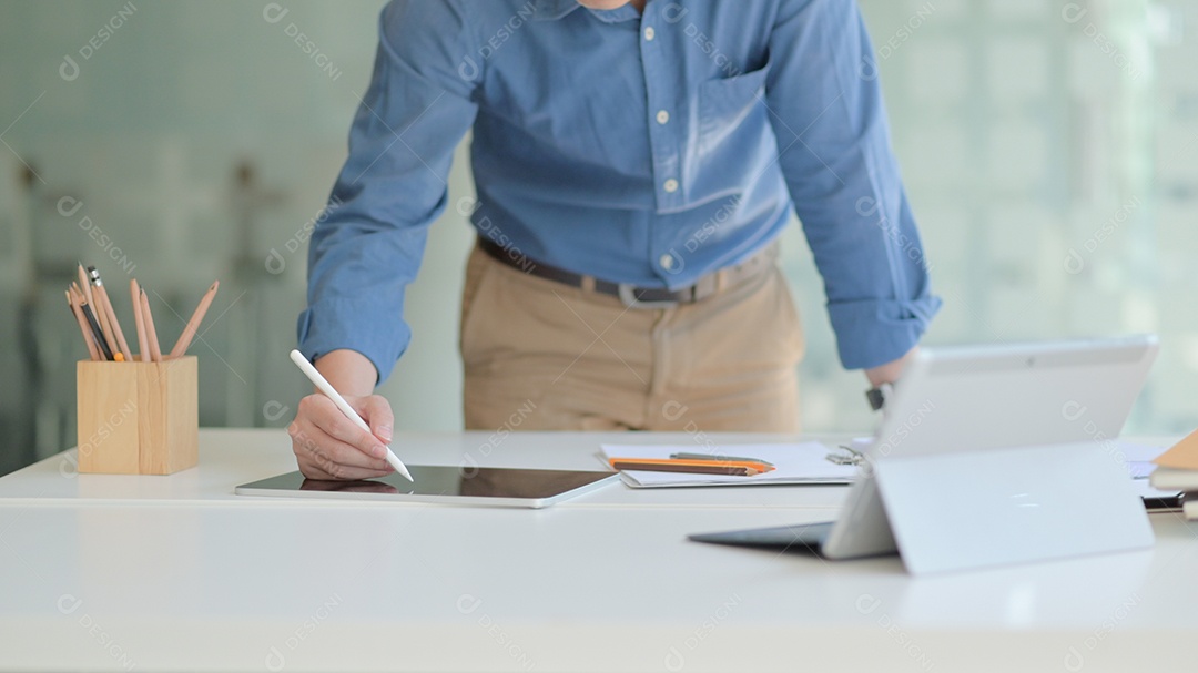 Foto recortada de Um designer profissional está trabalhando em um tablet moderno para projetar seu futuro projeto em um escritório confortável.