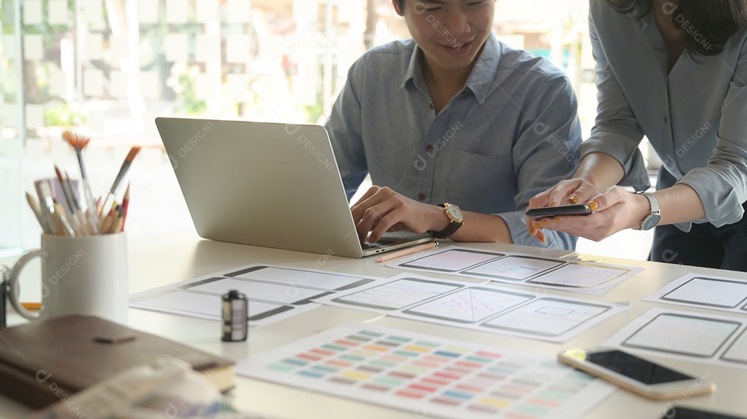 Foto recortada de Uma equipe de designers profissionais está trabalhando com smartphones e laptops para projetar aplicativos.