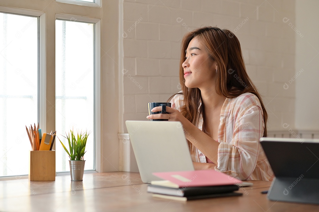 Retrato de jovem estudante alegremente bebe café enquanto lê para a preparação para o exame.