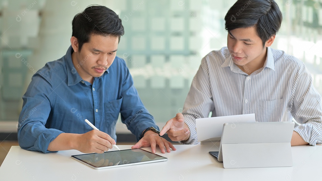 Foto recortada de dois homens asiáticos usando tablet para criar seu trabalho para apresentar aos clientes em um escritório contemporâneo.